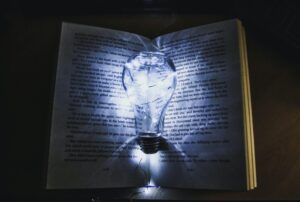 A blue light bulb lighting over a book in a dark room