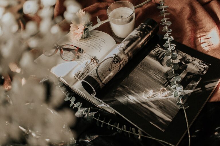 Notebook and rolled up magazine with glasses and a tea light beside them.