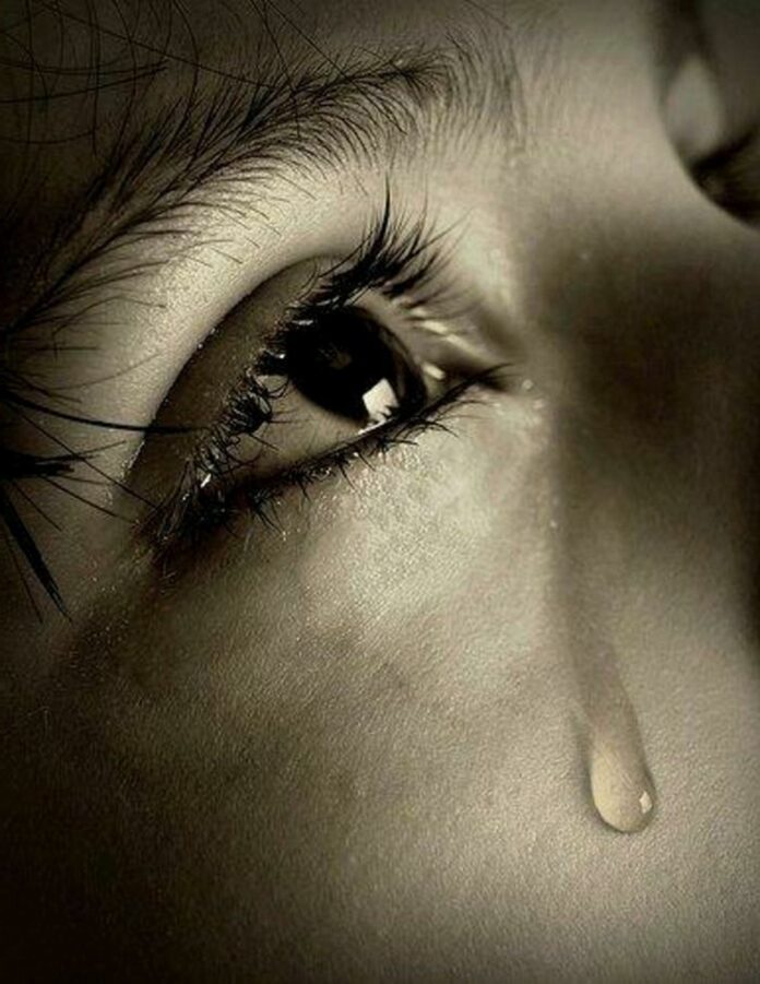 Close-up image of a person's eye, with a singular tear running down their face.