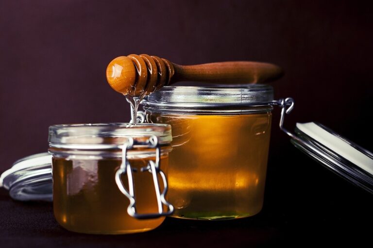 two honey jars with honey dipper on top of them