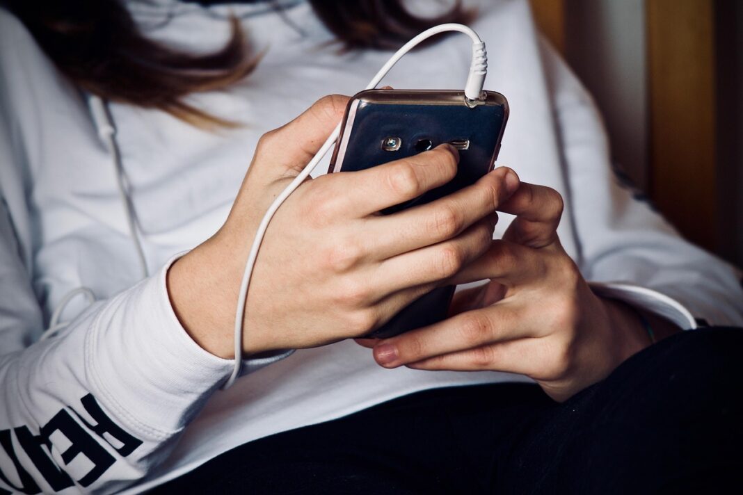 Woman listening to headphones through mobile phone