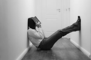 person with book over their face while reading in a hallway