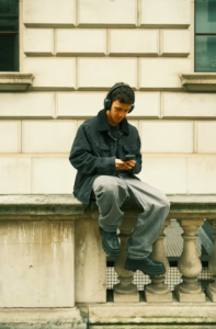 A man sitting on a ledge looking at his cell phone photo - Music Image on Unsplash