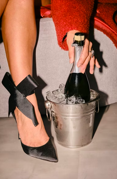 Women in heels hold champagne bottle chilling in ice bucket. photo – Celebration Image on Unsplash
